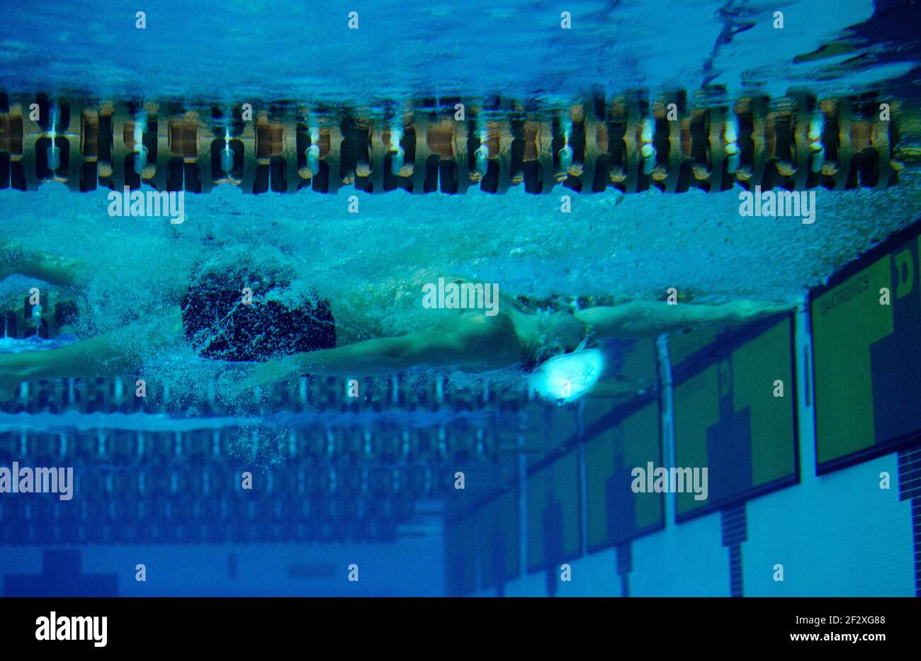 Un nuotatore maschile a corsa di ritorno nuota sott'acqua al turn in una piscina olimpionica. Foto Stock