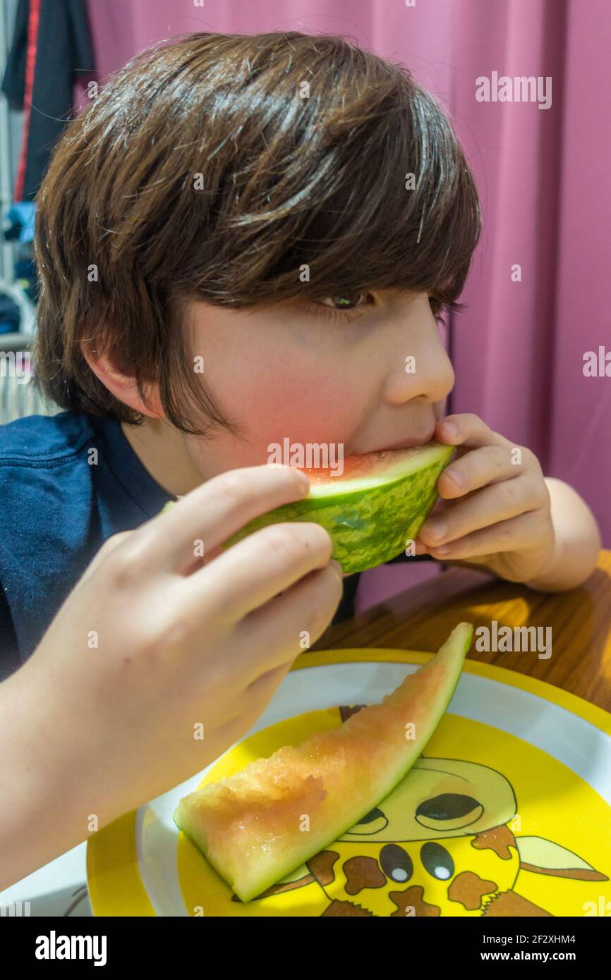 Un ragazzo che mangia una fetta di anguria. Foto Stock