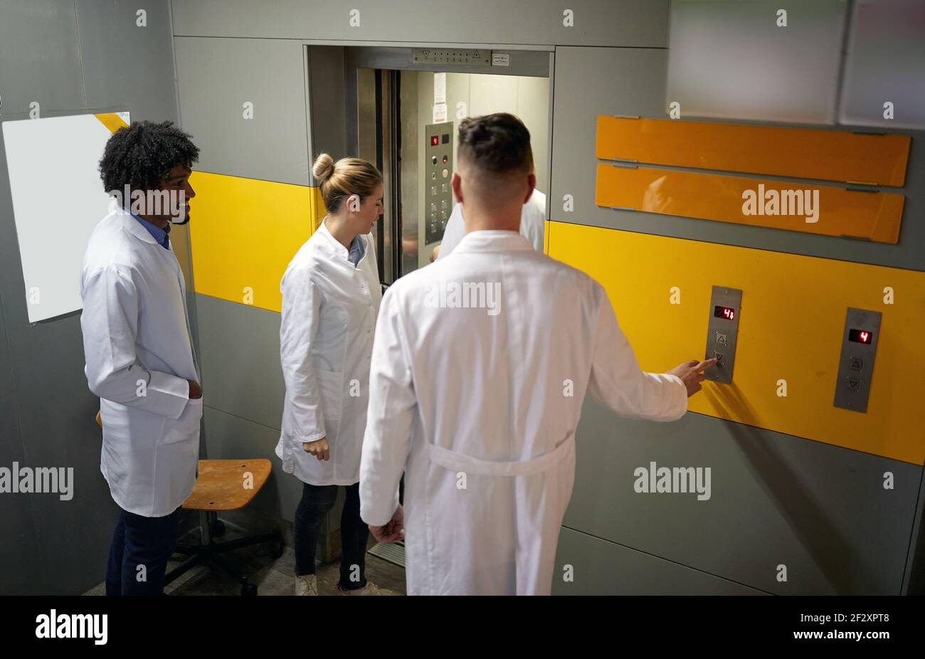 Gruppo di giovani internisti medici che entrano nell'ascensore Foto Stock