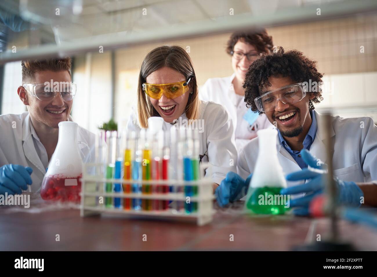 Giovani studenti di chimica che si divertono in un ambiente di laboratorio sterile mentre si godono le reazioni chimiche colorate. Scienza, chimico Foto Stock