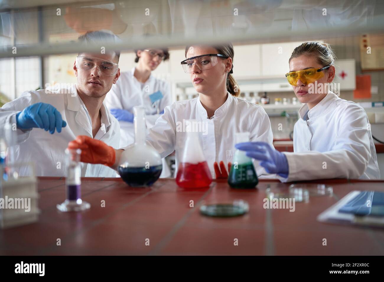 Tecnici di laboratorio che esaminano le reazioni chimiche in laboratorio Foto Stock