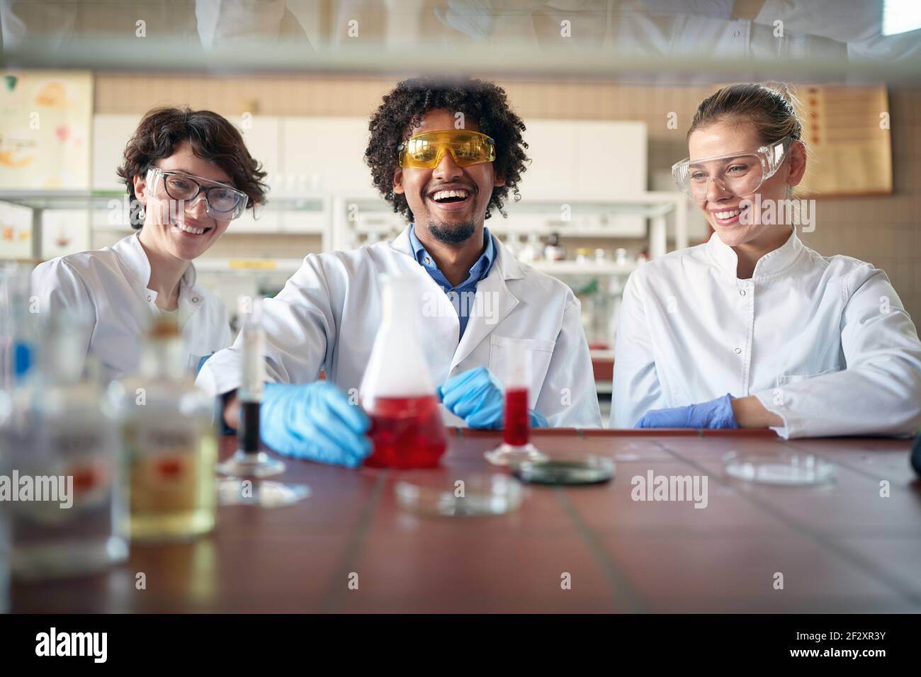 I giovani studenti di chimica si divertono a lavorare con le sostanze chimiche in un'atmosfera allegra nel laboratorio universitario. Scienza, chimica, laboratorio, persone Foto Stock