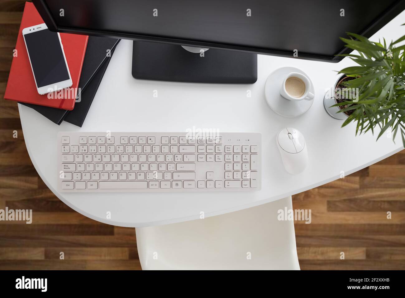 Da sopra computer e smartphone moderni con notebook posizionato sopra tavolo bianco in ufficio leggero Foto Stock
