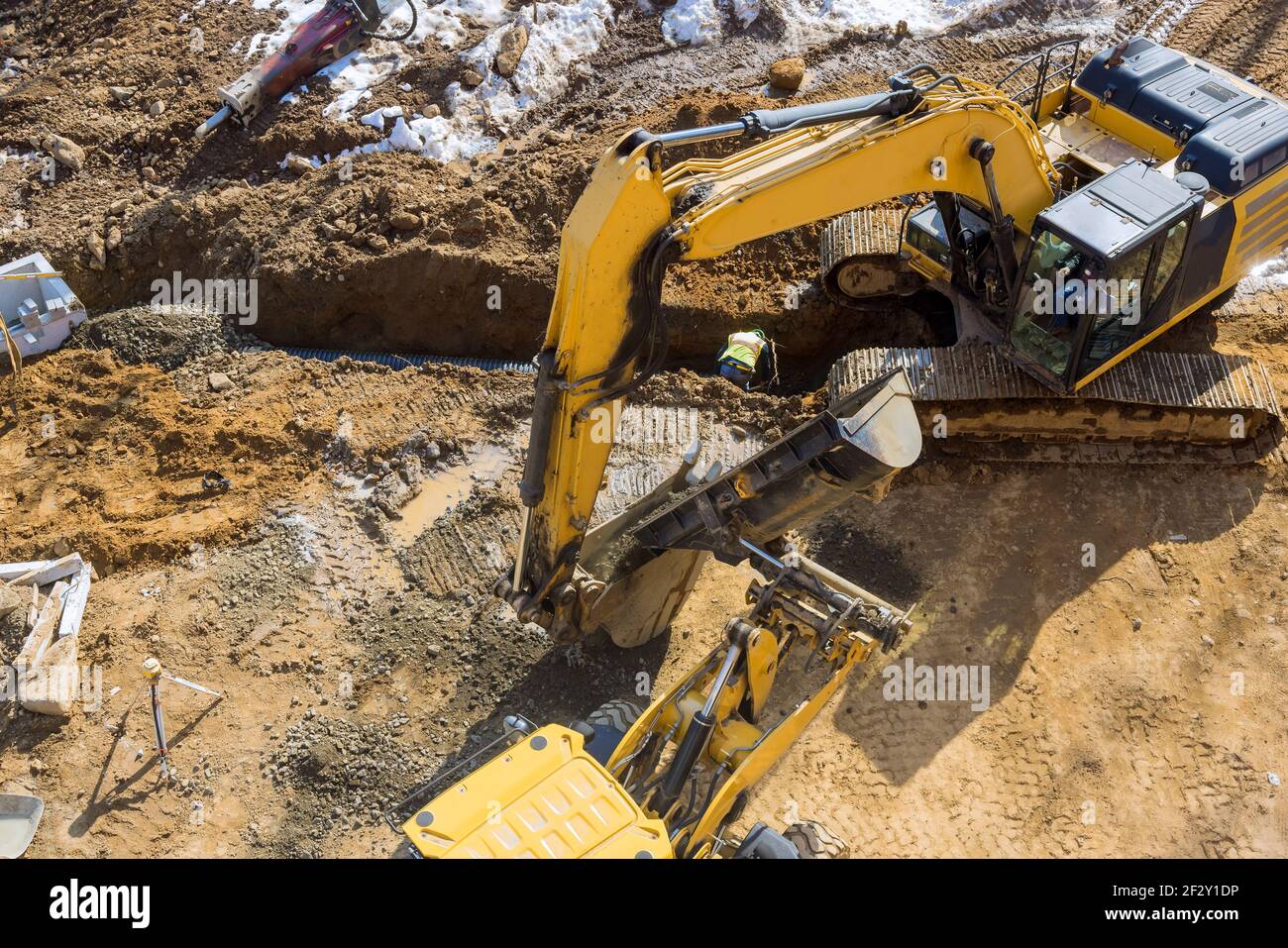 Scavatore scavare trincea in cantiere posando pozzi fognari e. tubi fognari Foto Stock