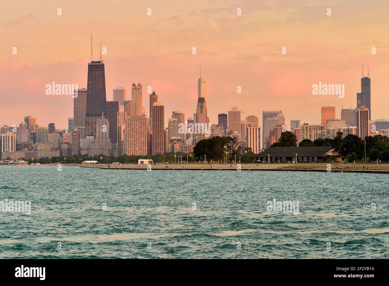 Chicago, Illinois, Stati Uniti. Appena prima del tramonto, la luce viene proiettata nelle nuvole e si riflette su un certo numero di edifici nello skyline in una serata estiva. Foto Stock