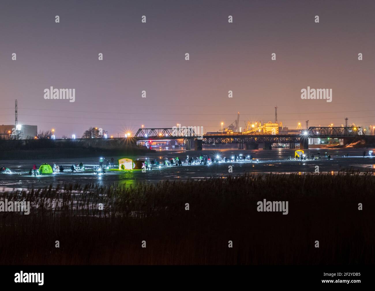 i pescatori di fiume, di notte e di ghiaccio pescano al buio con luci artificiali e tutti si siedono uno dopo l'altro in una striscia nel mezzo del sonno Foto Stock