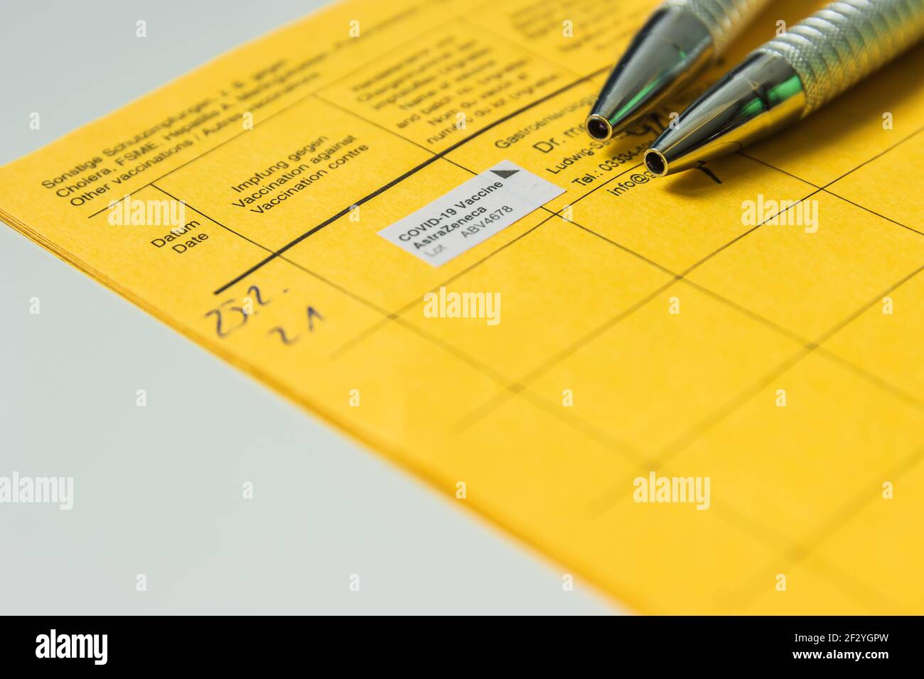 Pagina dal libro di vaccinazione con prova di vaccinazione contro il coronavirus e due penne a sfera. Azienda medica con numero di lotto nella vaccinazione Foto Stock