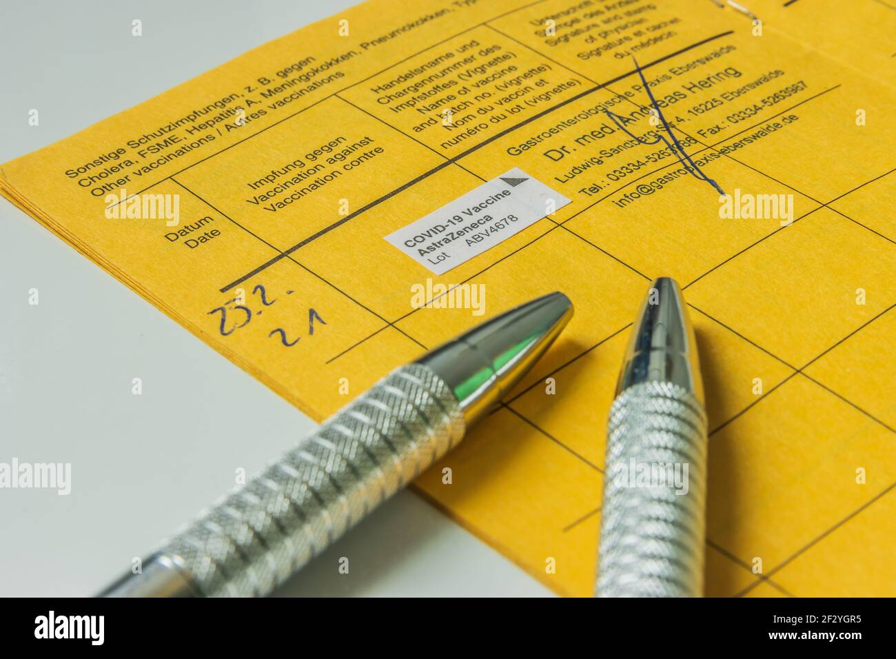 Libro di vaccinazione con prova contro il coronavirus. Due penne a sfera sulla pagina del libro di vaccinazione. Azienda medica con numero di lotto nella vaccinazione Foto Stock