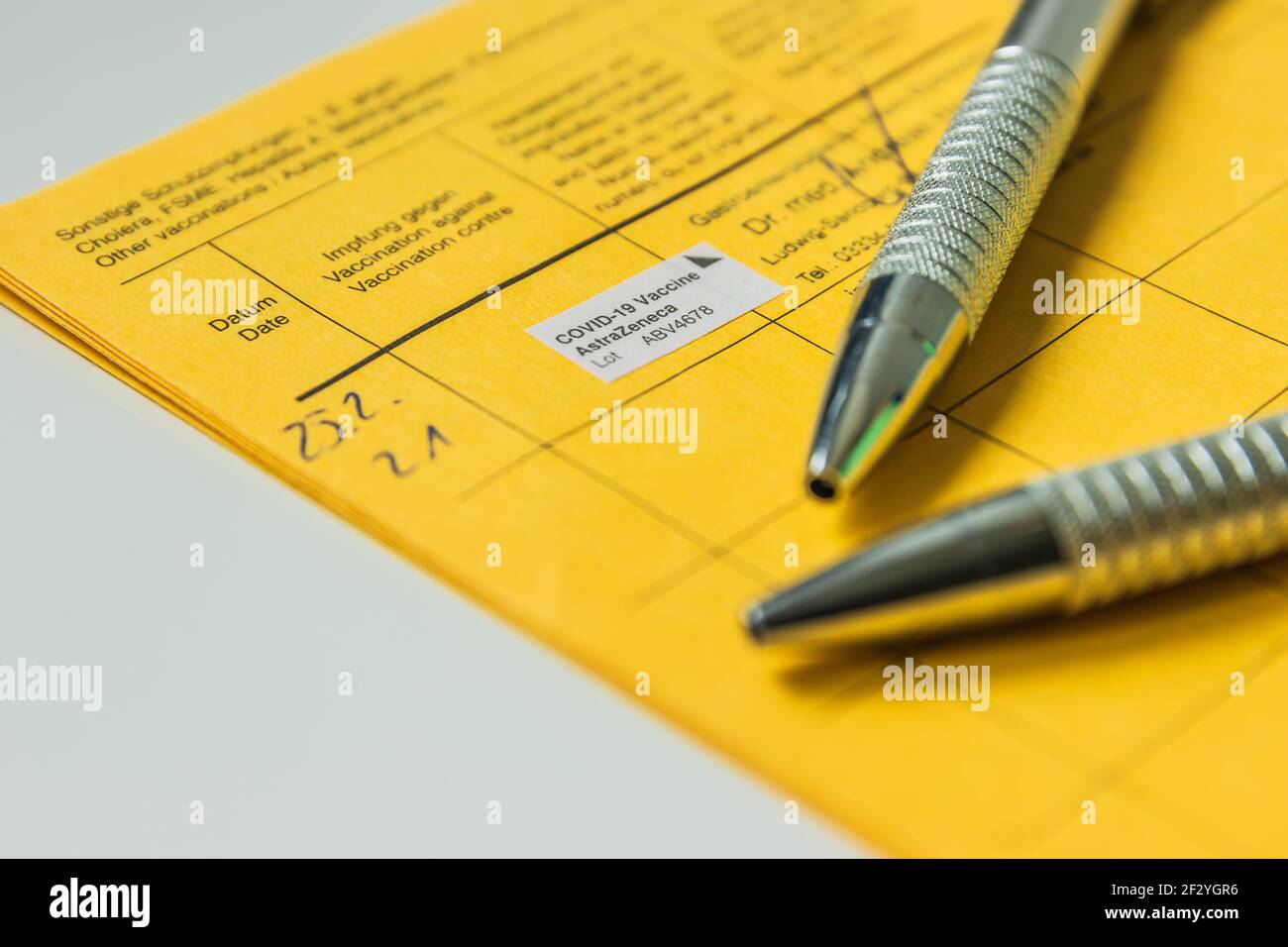 Due penne su una pagina di un libro di vaccinazione con la prova di vaccinazione contro il coronavirus. Azienda medica con il numero di lotto nel registro di vaccinazione Foto Stock