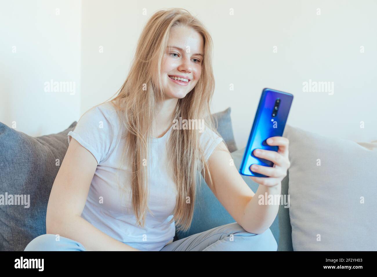 Ragazza giovane e sorridente che ha una videochiamata mentre è in auto-isolamento Foto Stock