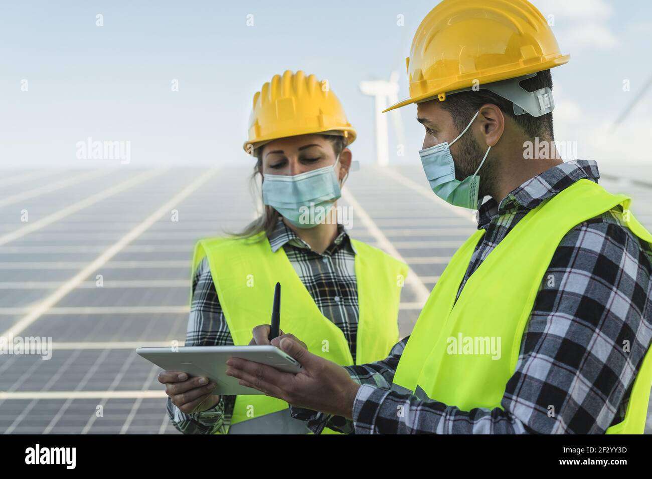 Persone che lavorano per l'energia alternativa con turbine eoliche e solari pannello mentre si indossa la maschera facciale durante l'epidemia di virus corona Foto Stock Persone che lavorano per l'energia alternativa con turbine eoliche e solari pannello mentre si indossa la maschera facciale durante l'epidemia di virus corona Foto Stock
