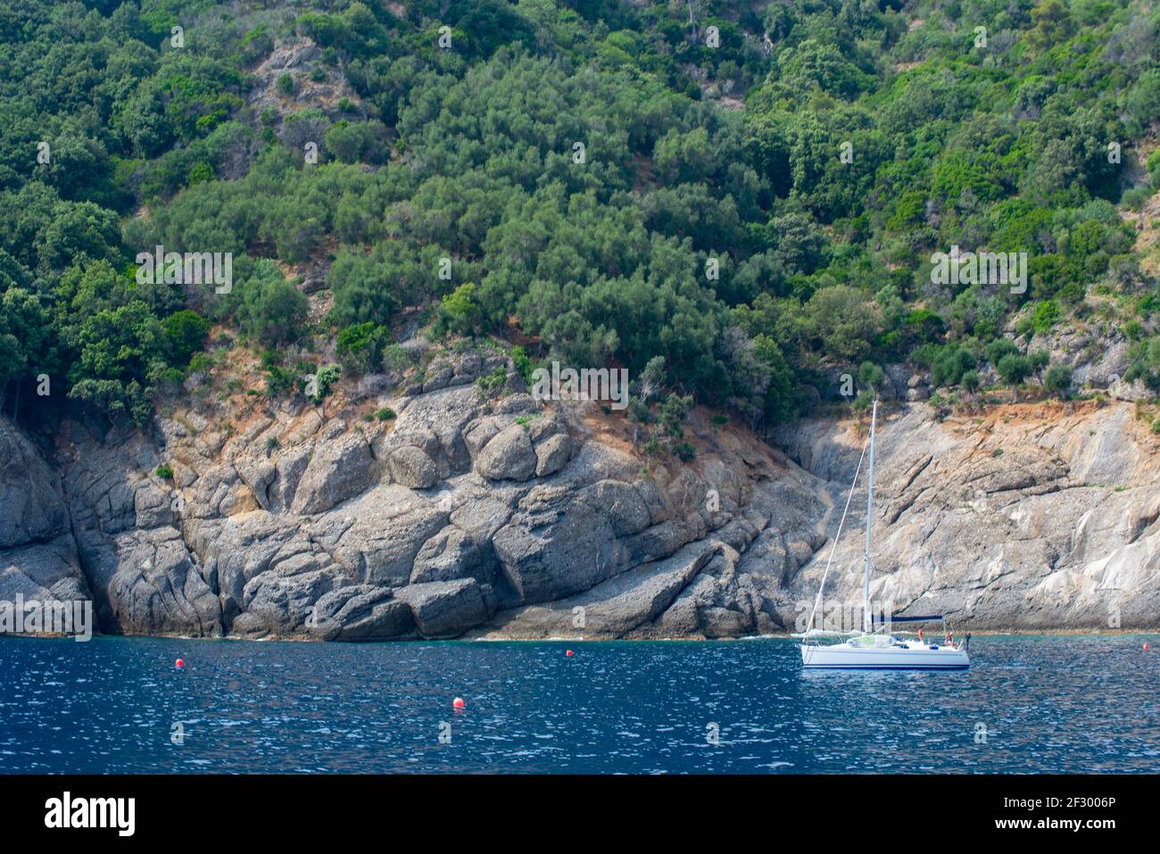 La barca a vela bianca naviga nel mare ligure accanto al promontorio di Portofino. E' una riserva marina dove il mare è molto limpido Foto Stock