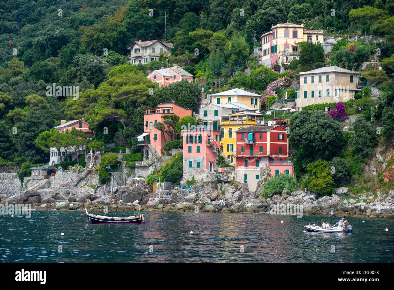 Case e ville colorate sulla costa vicino a Porto Pidocchio. Barca di legno ormeggiata e una barca gonfiabile Foto Stock