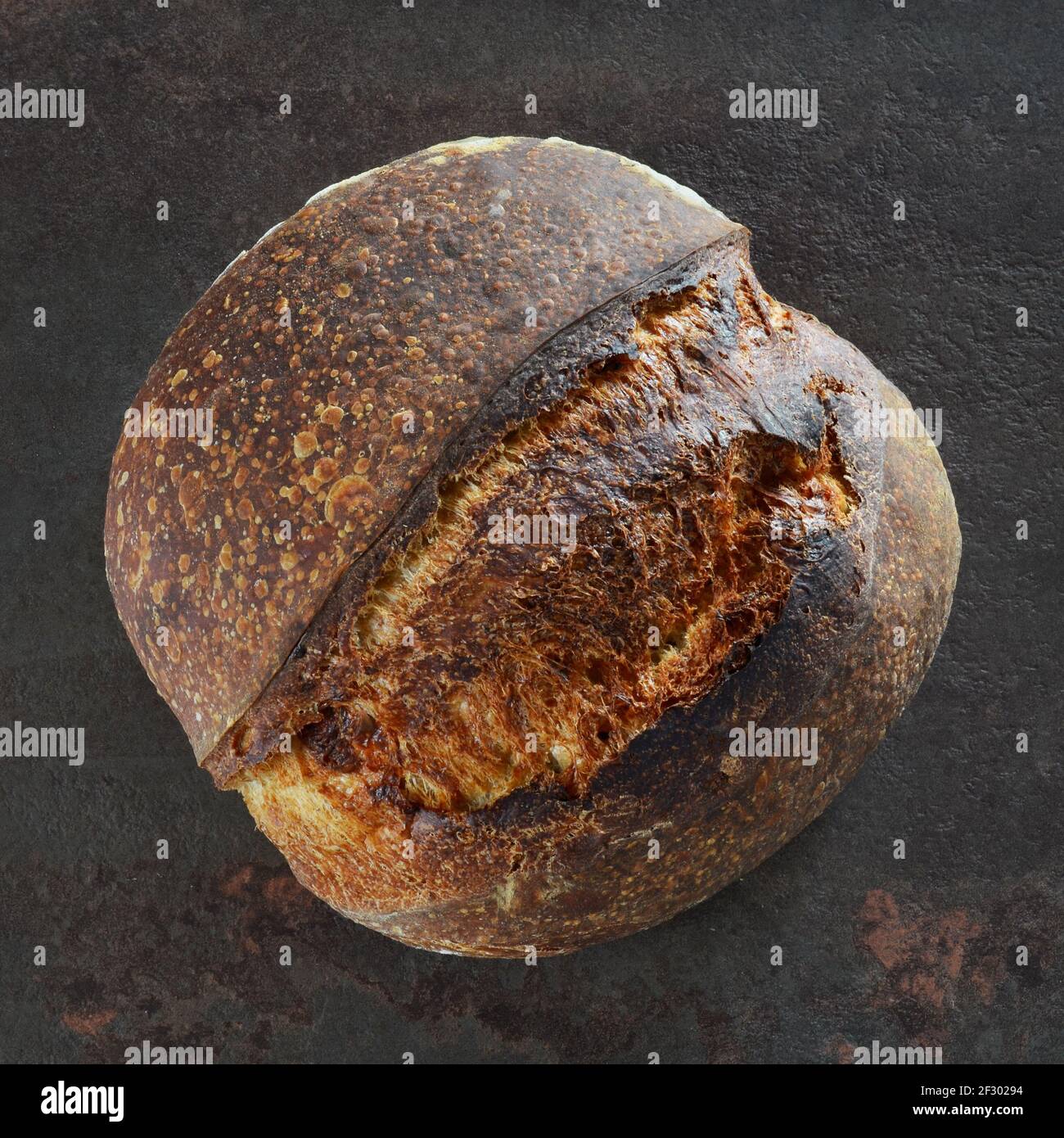 Pane fatto in casa appena sfornato con crosta croccante su uno sfondo scuro primo piano Foto Stock