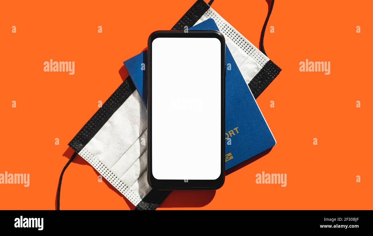 Concetto di viaggio moderno, schermo bianco vuoto per smartphone. Display generico del telefono, maschera facciale e passaporto biometrico in rosso luminoso sfondo, spazio per la copia Foto Stock
