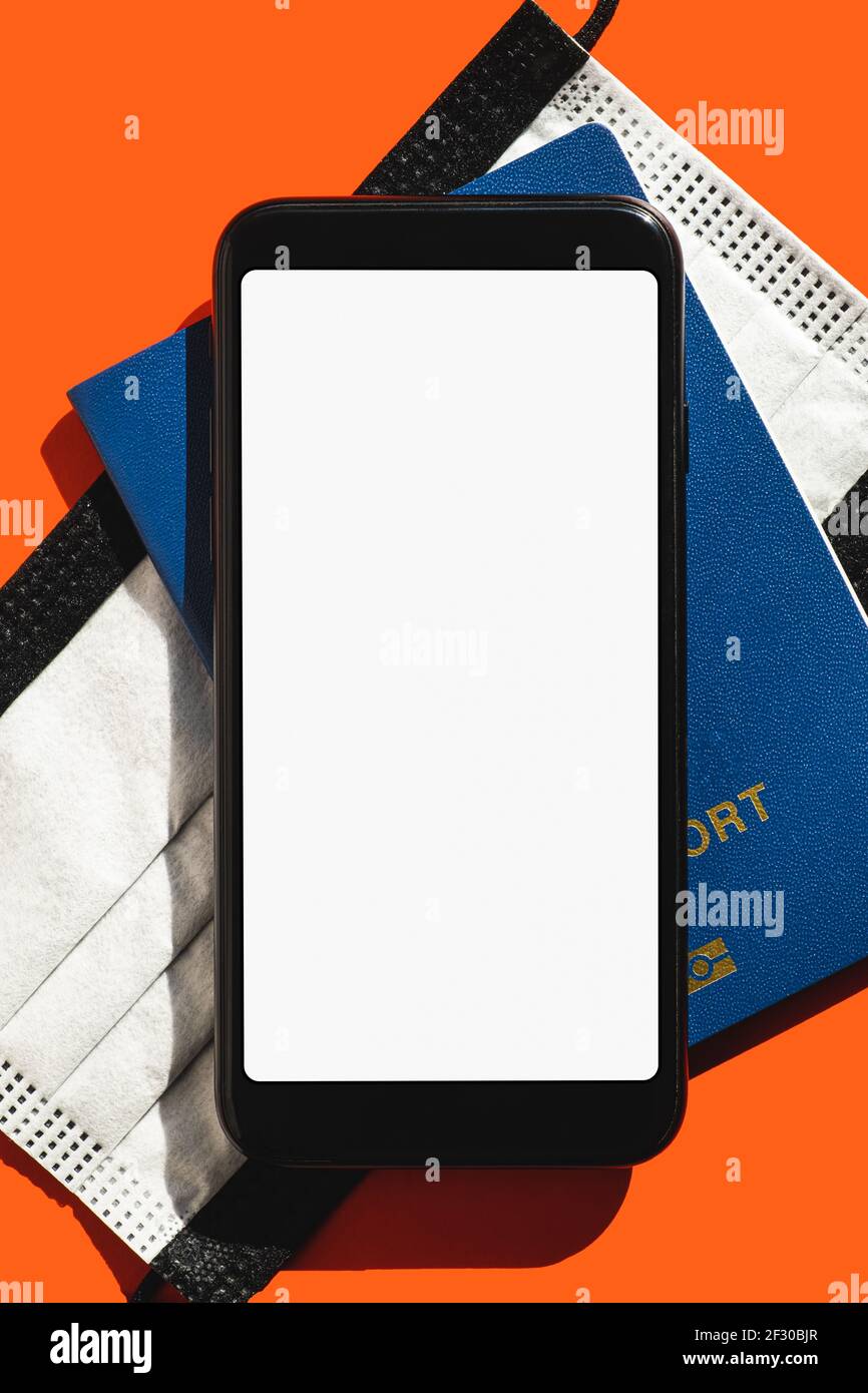 Concetto di viaggio moderno, schermo bianco vuoto per smartphone. Display generico del telefono, maschera facciale e passaporto biometrico in rosso luminoso sfondo, spazio per la copia Foto Stock