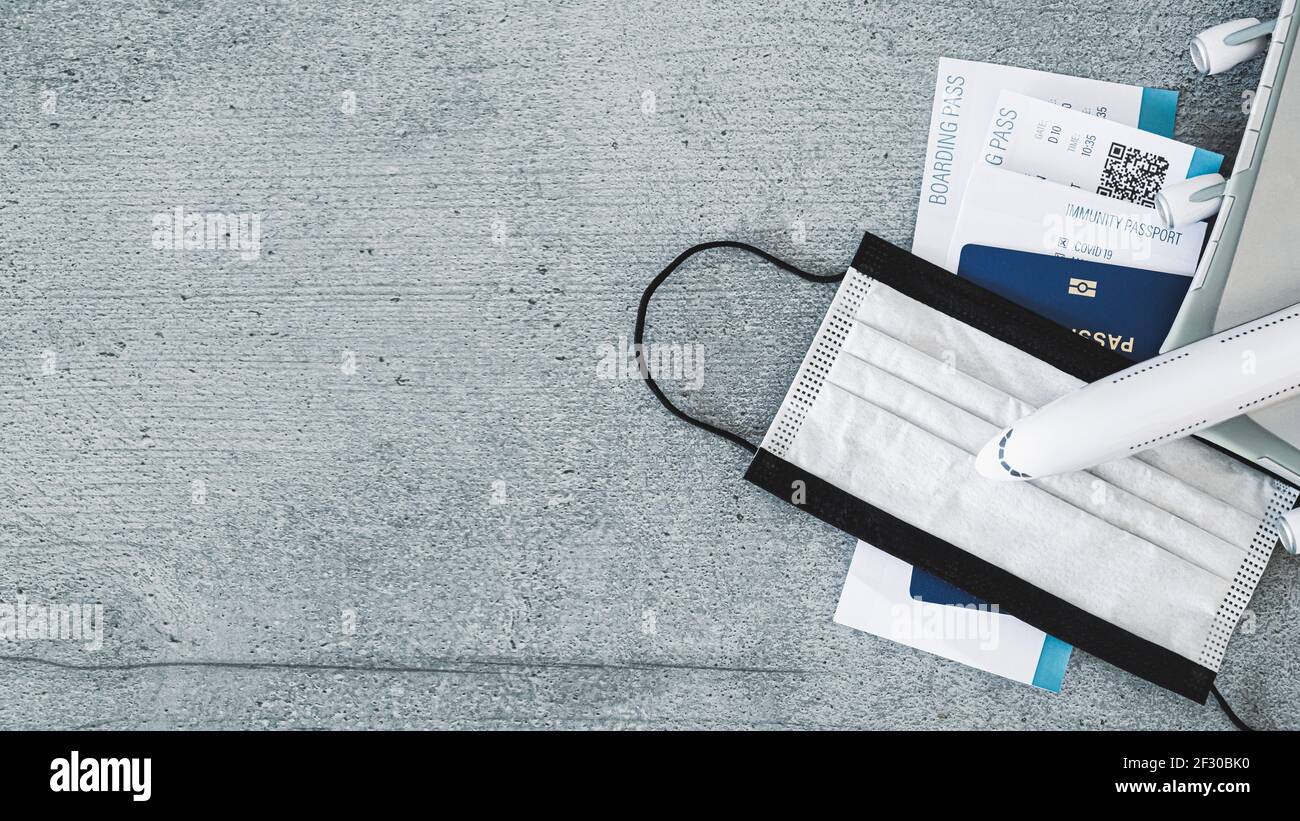 Generic post covid 19 Air Travel background. Modello di aereo, certificato di immunità, carta d'imbarco, passaporto di viaggio e maschera in legno grigio bac Foto Stock