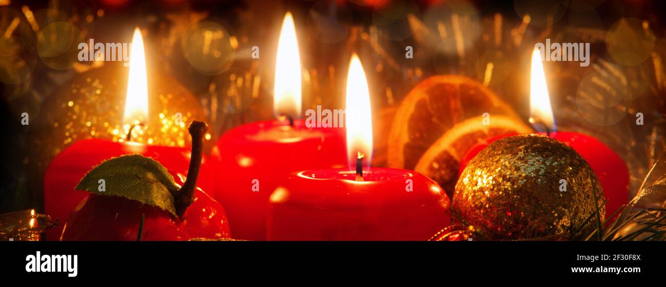 Quattro candele rosse con palla di natale in luce atmosferica. Foto Stock