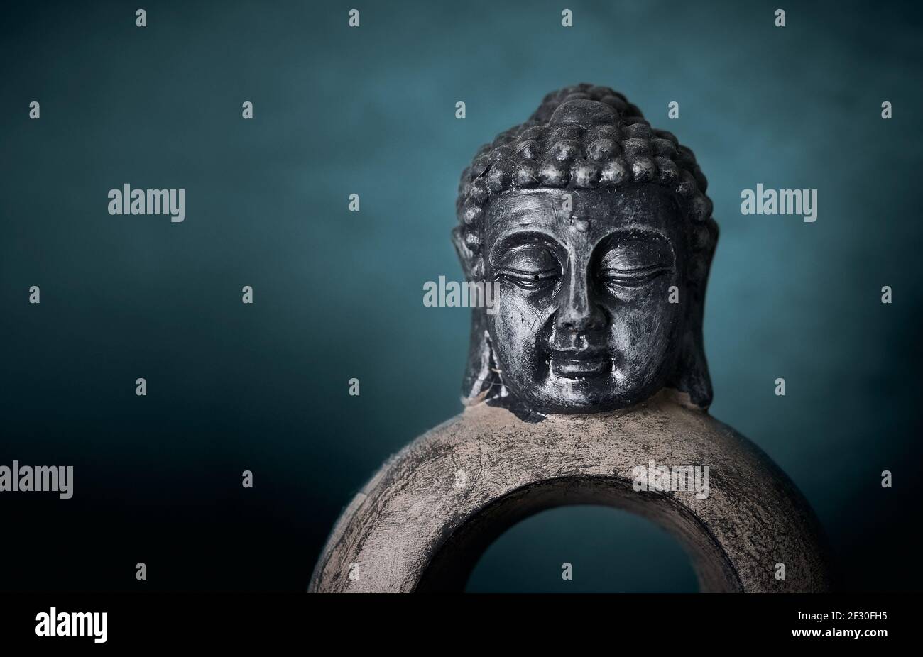 Primo piano di una scultura di Buddha su uno sfondo blu dello studio. Foto Stock