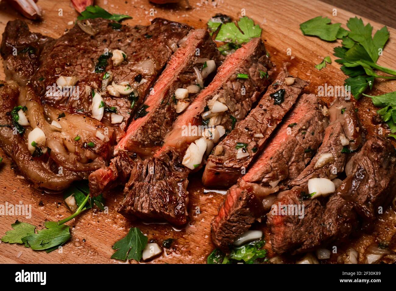 Bistecca di sirloin medio raro appena scottata sul tagliere tostata in burro, aglio, scalogno e prezzemolo Foto Stock