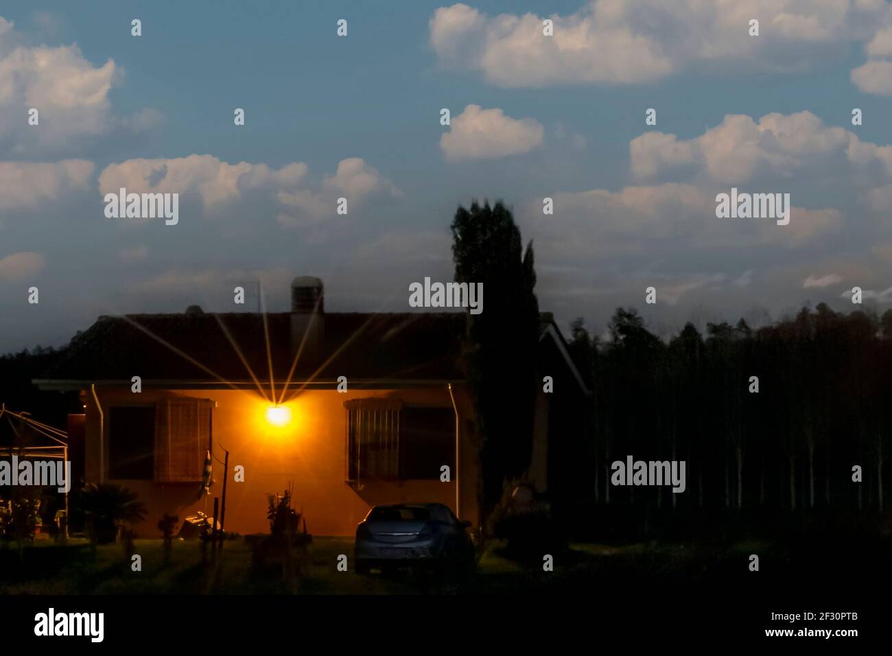 Una casa gialla nelle tenebre contro un cielo blu con nuvole bianche in campagna Foto Stock