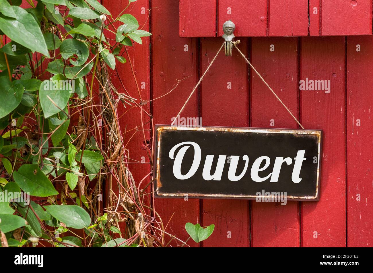 Vecchio segno di metallo con l'iscrizione aperto in francese - Ouvert Foto Stock