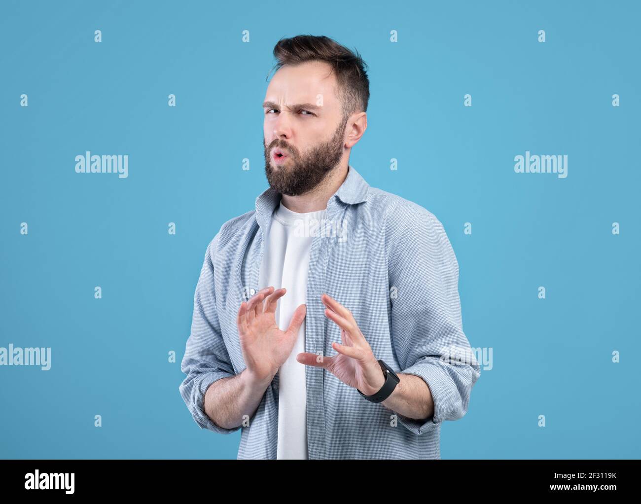 Disgustato giovane ragazzo rifiutando qualcosa, gesturing NO o STOP su sfondo blu studio Foto Stock