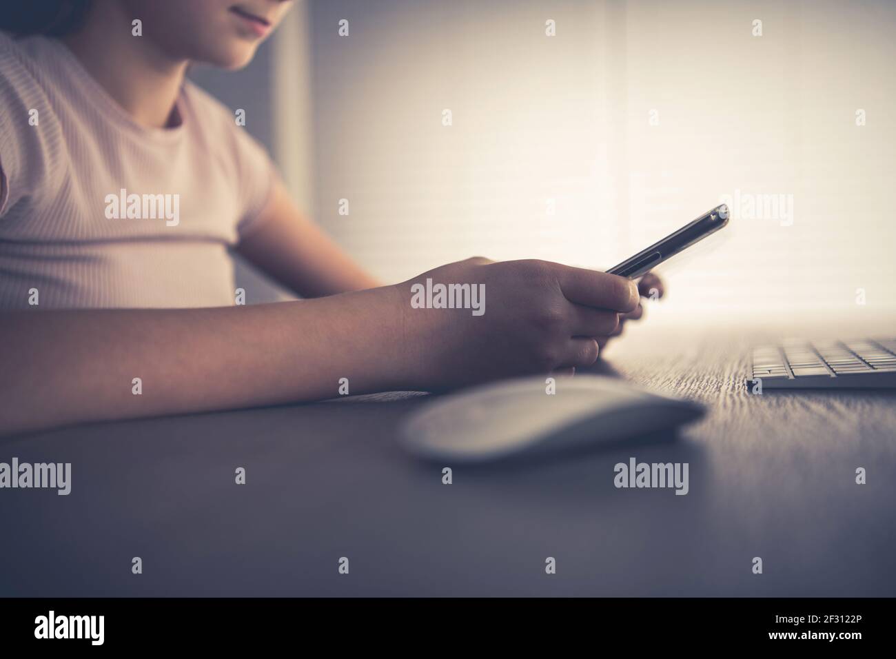 Ragazza caucasica che gioca con il suo moderno smartphone collegando il dispositivo mobile al Personal Desktop computer. Tecnologie mobili e wireless. Primo piano Foto Stock