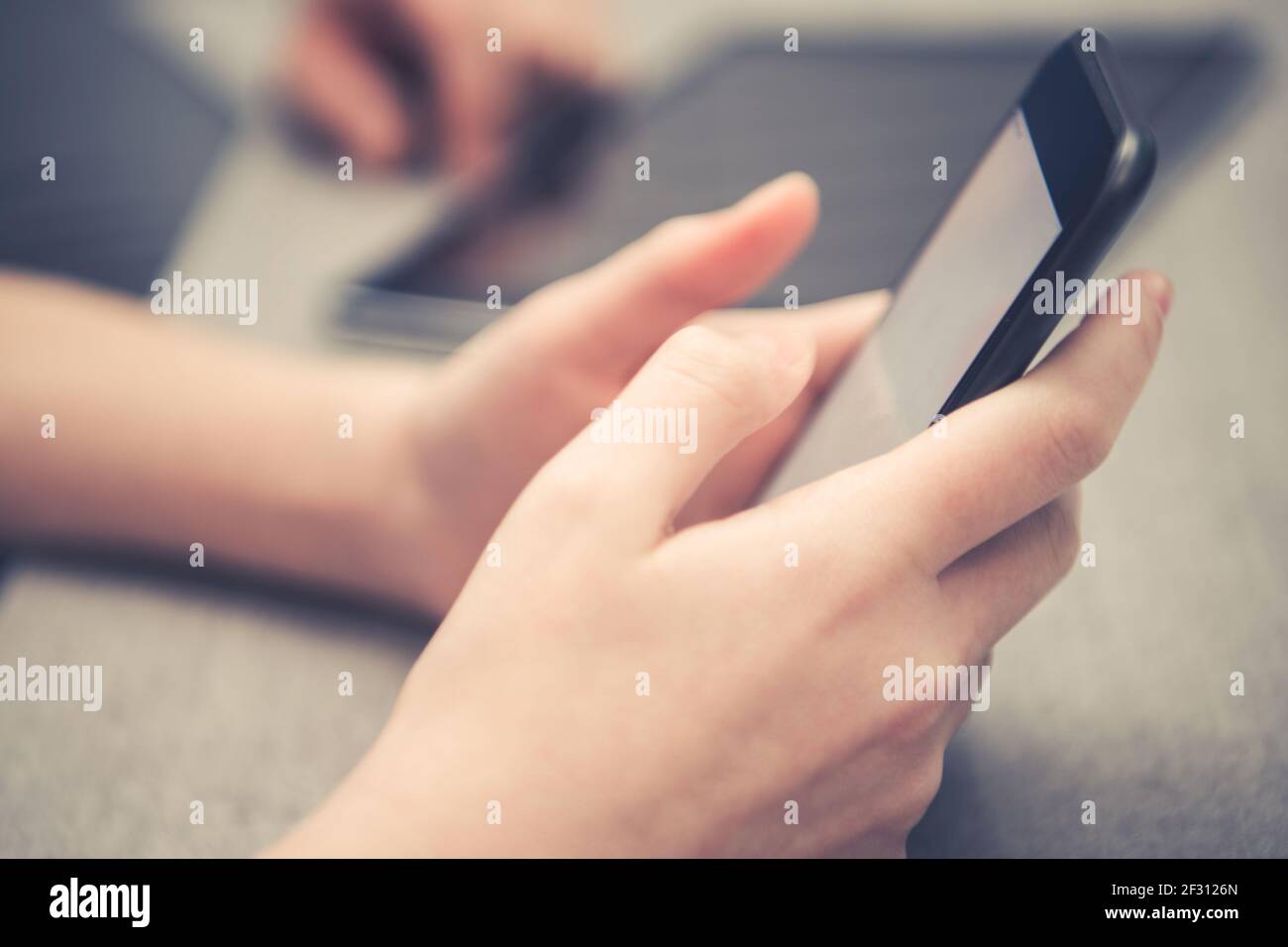 Ragazza caucasica giocando con il suo telefono. Smartphone moderno in mani Kid. Tema comunicazione moderna. Foto Stock