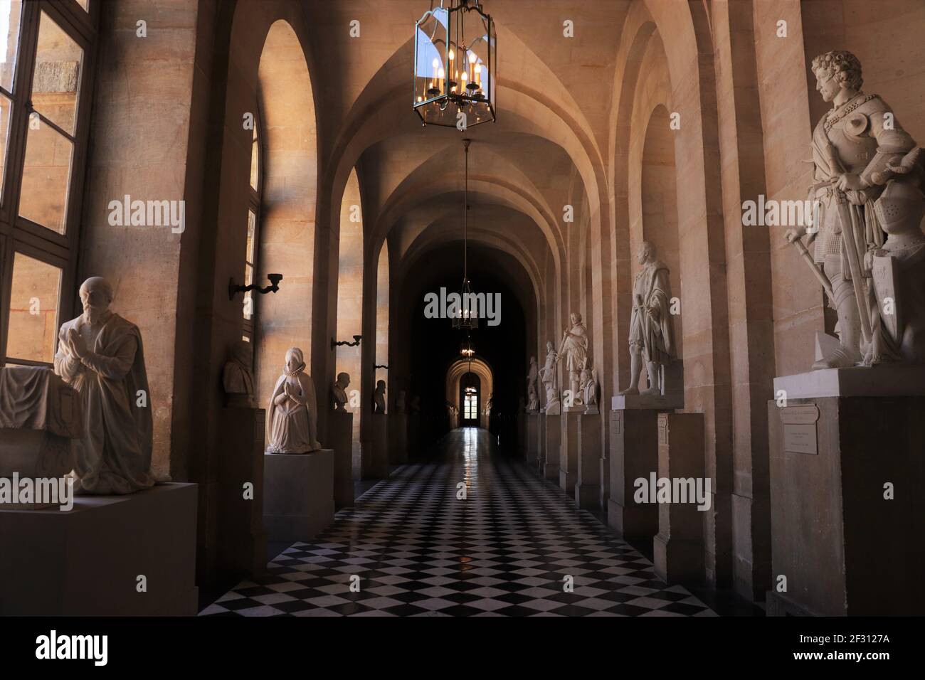 Tranquillo corridoio Dim fiancheggiato da statue alla Reggia di Versailles, Francia Foto Stock