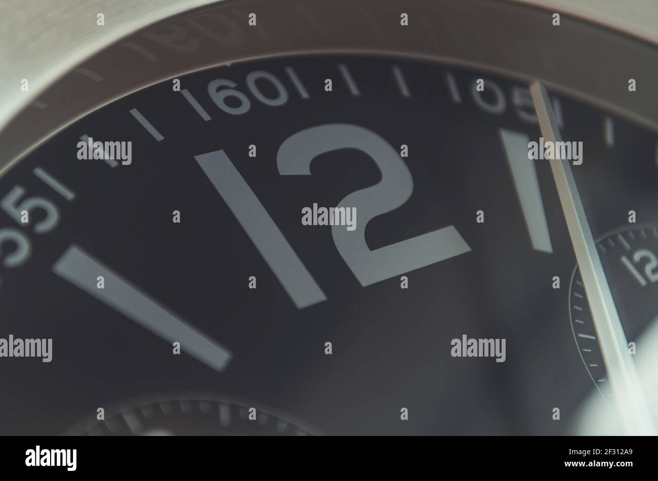 Dodici o'Clock orologio da parete tempo primo piano su foto. Orologio industriale in custodia in alluminio. Foto Stock