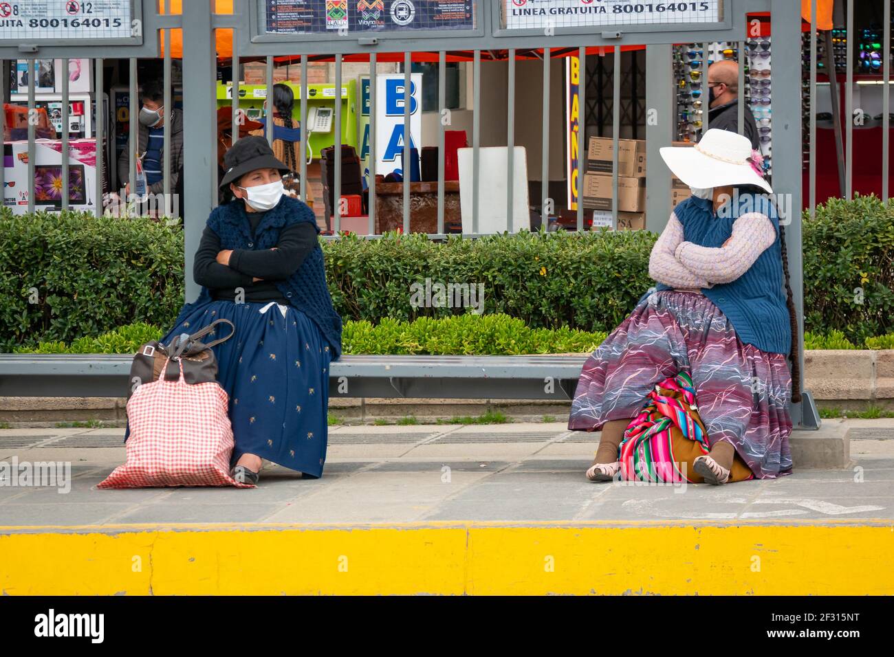 El Alto, la Paz, Bolivia - Febbraio 11 2021: Le donne indigene boliviane conosciute come 'Cholitas', sedendosi su un banco un metro di distanza l'una dall'altra mentre noi Foto Stock