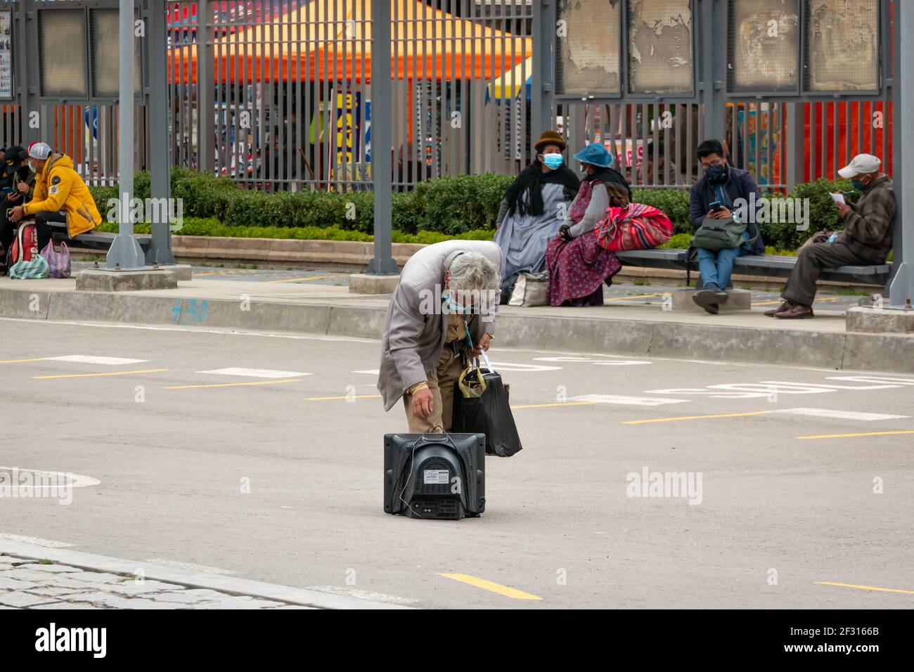 El Alto, la Paz, Bolivia - Febbraio 11 2021: L'uomo latino anziano che indossa una maschera dal Covid-19, sta portando un set televisivo antico e una borsa nell'Othe Foto Stock