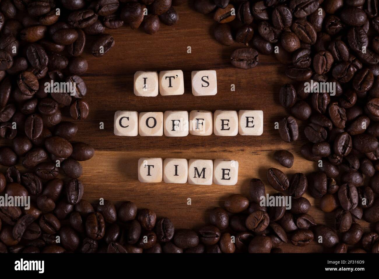 è il momento del caffè con lettere cubiche di legno e caffè tutto intorno su un tavolo di legno. aroma di caffè fresco. Foto Stock