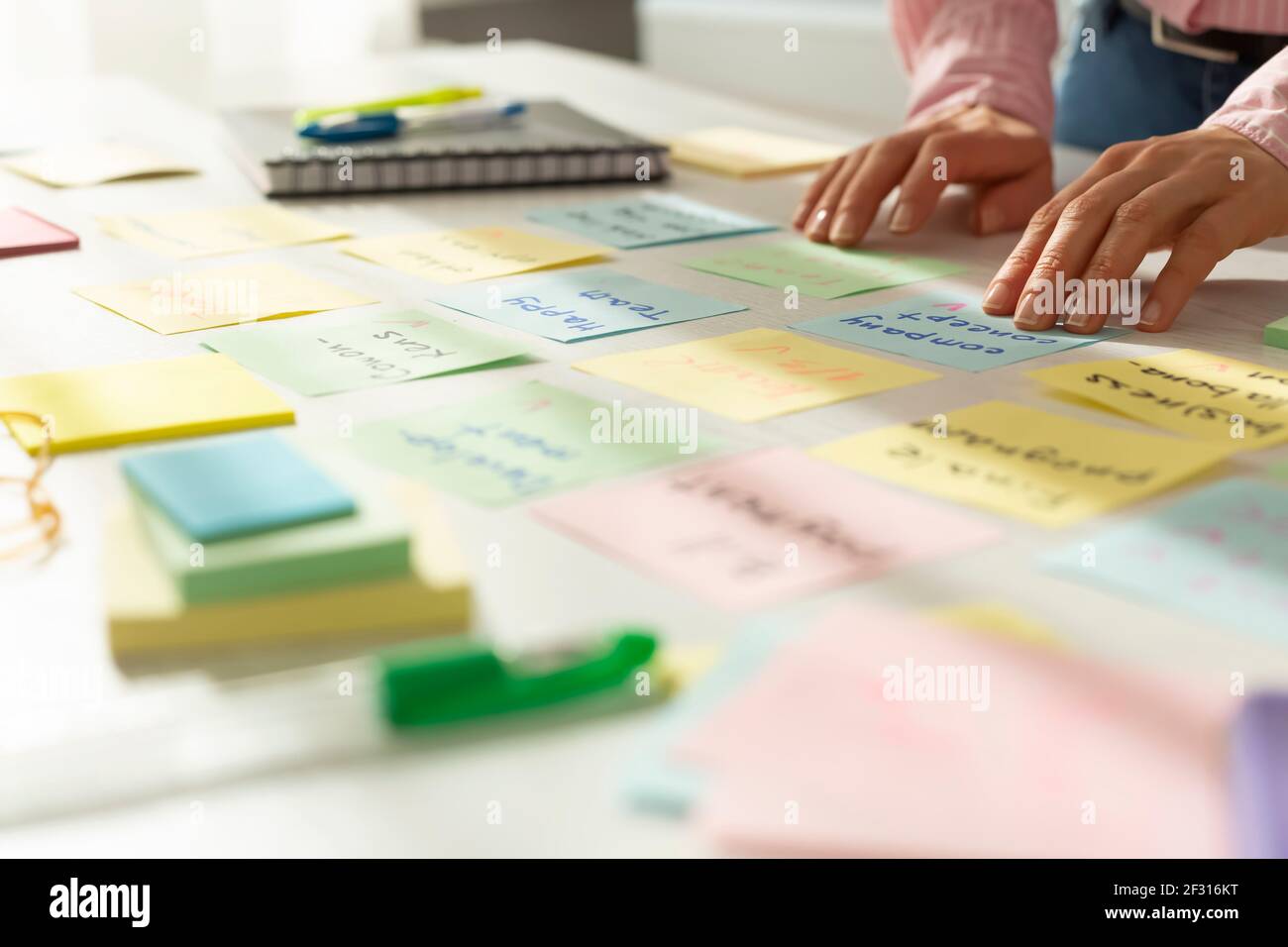Le mani della donna d'affari scrivono le note sugli adesivi sul desktop. Foto Stock
