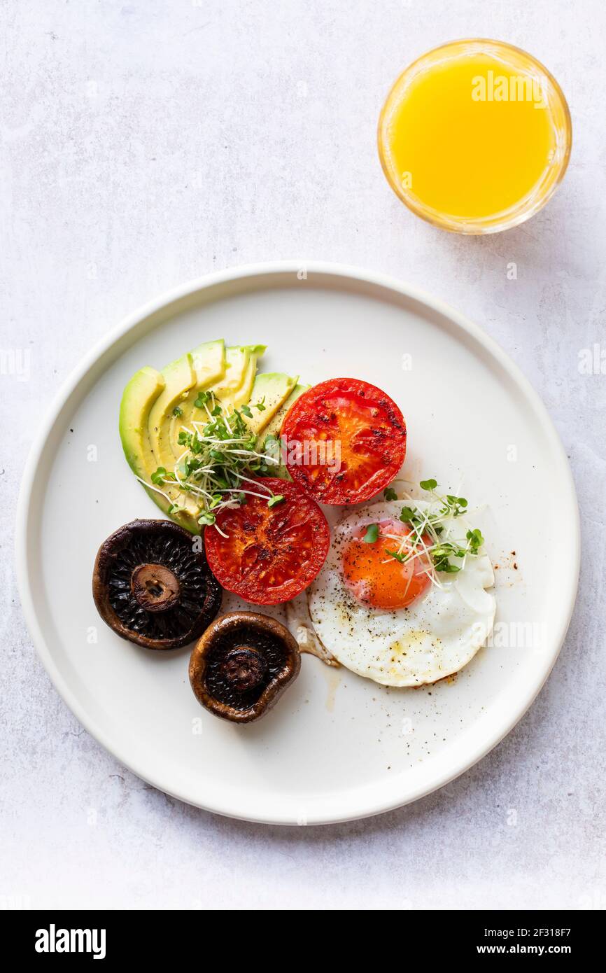 Colazione vegetariana con uova fritte, pomodori, funghi e avocado Foto Stock