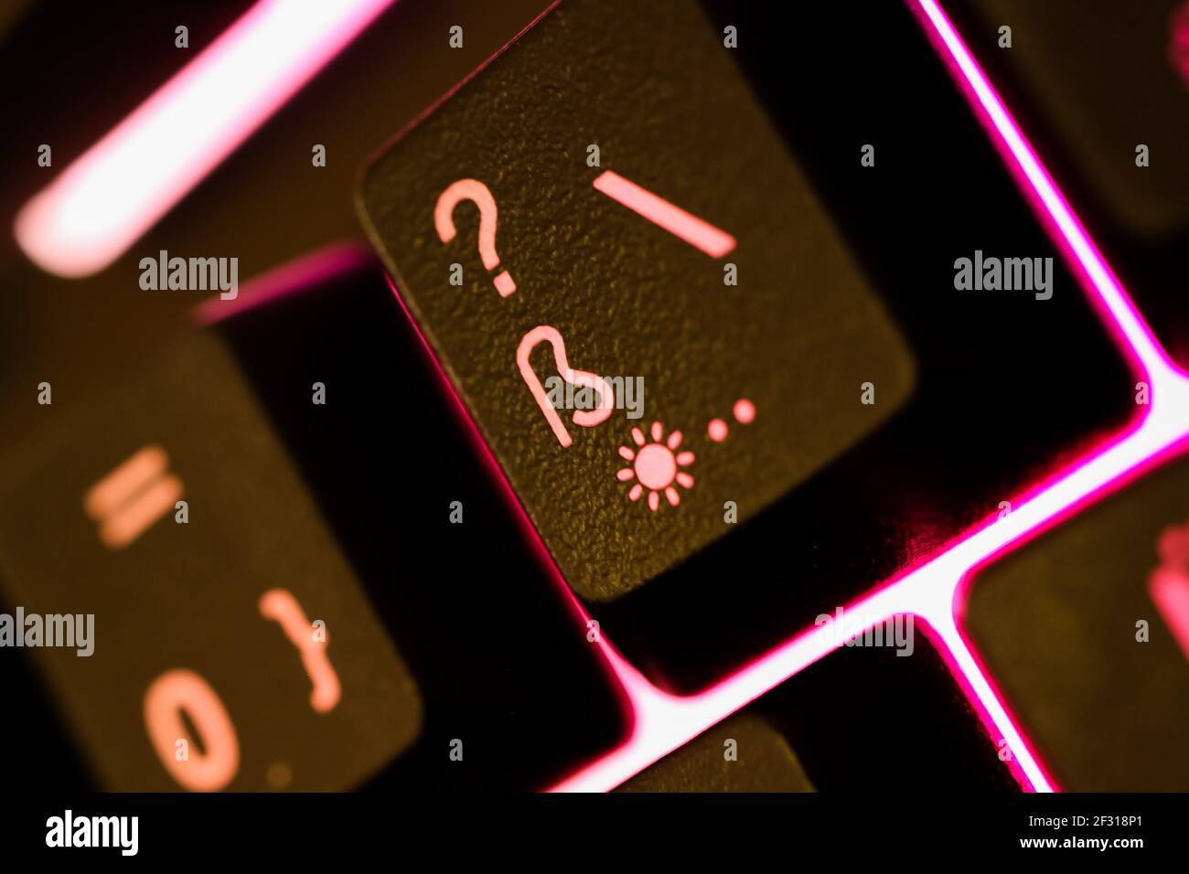 Makro closeup del tasto illuminato rosa sulla tastiera del computer con caratteri speciali (fuoco selettivo sulla parte sinistra del simbolo ß) Foto Stock