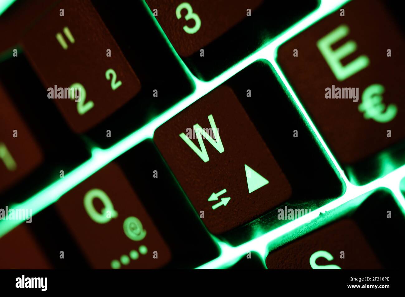 Makro primo piano di tasti verdi illuminati per la tastiera del computer con lettere, numeri e caratteri speciali (focus sul tasto con la lettera W) Foto Stock
