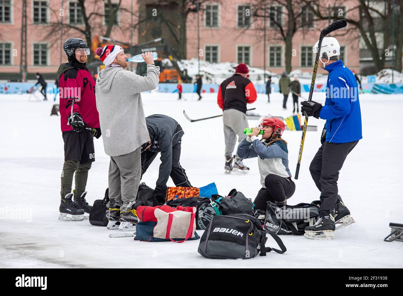 Amici che hanno una pausa e un drink d'acqua dopo una partita amichevole di hockey su ghiaccio alla pista di pattinaggio di Brahenkenttä a Helsinki, Finlandia Foto Stock