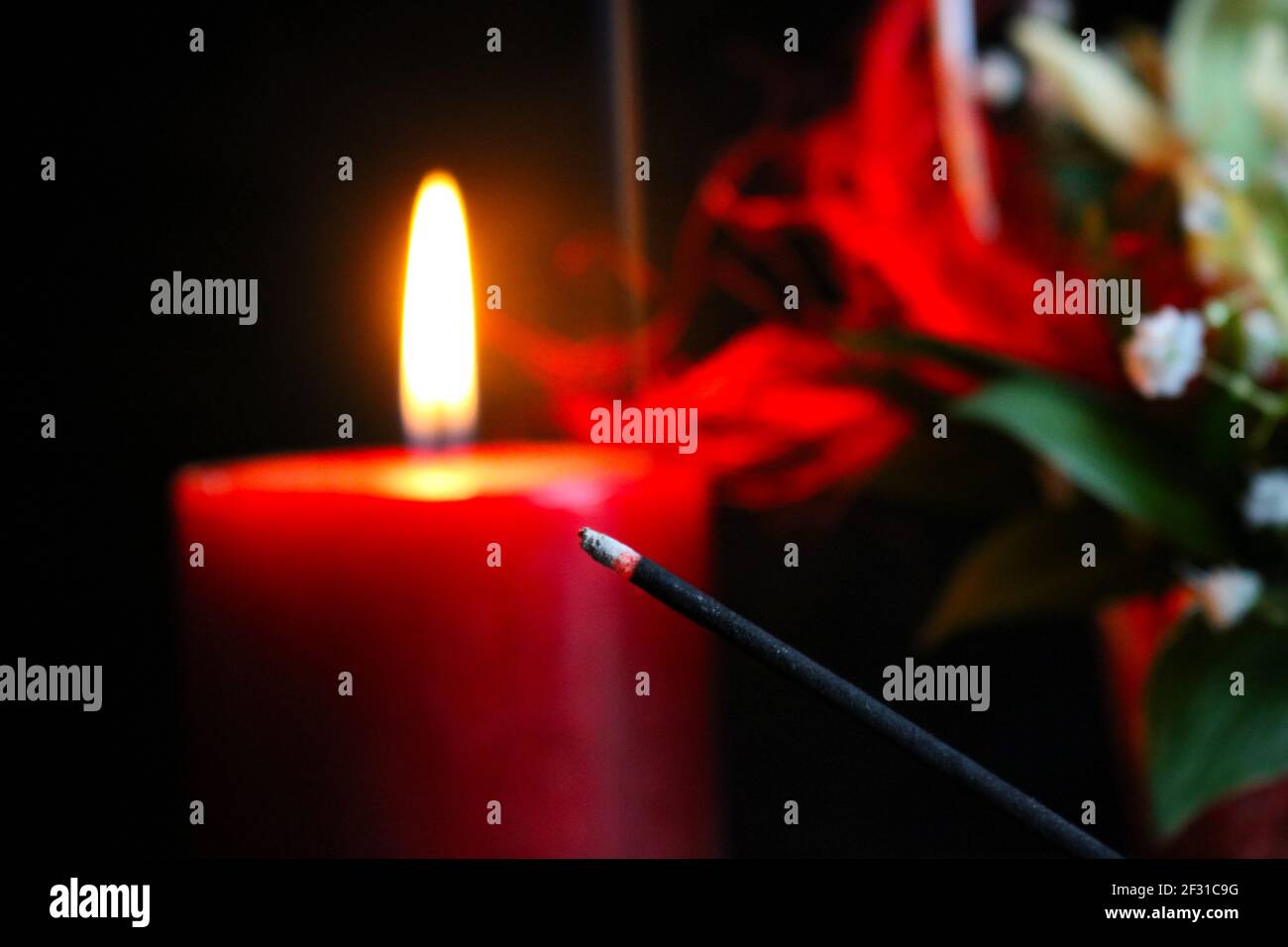Candela rossa, fiori e bastone profumato Foto Stock
