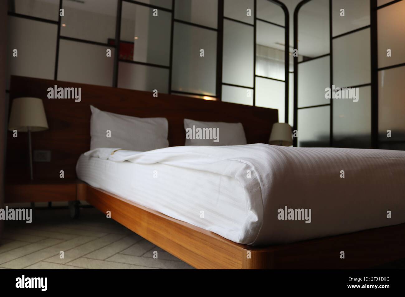 Camera da letto con pareti in vetro e letto matrimoniale. Letto con lati in legno. Foto Stock