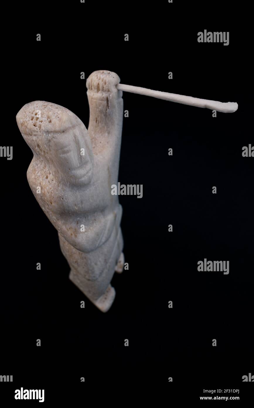 Piccola statua del cacciatore inuit con una lancia fatta di osso animale. Isolato su sfondo nero. Arte inuit Cultura tribale dei nativi nell'estremo nord Foto Stock