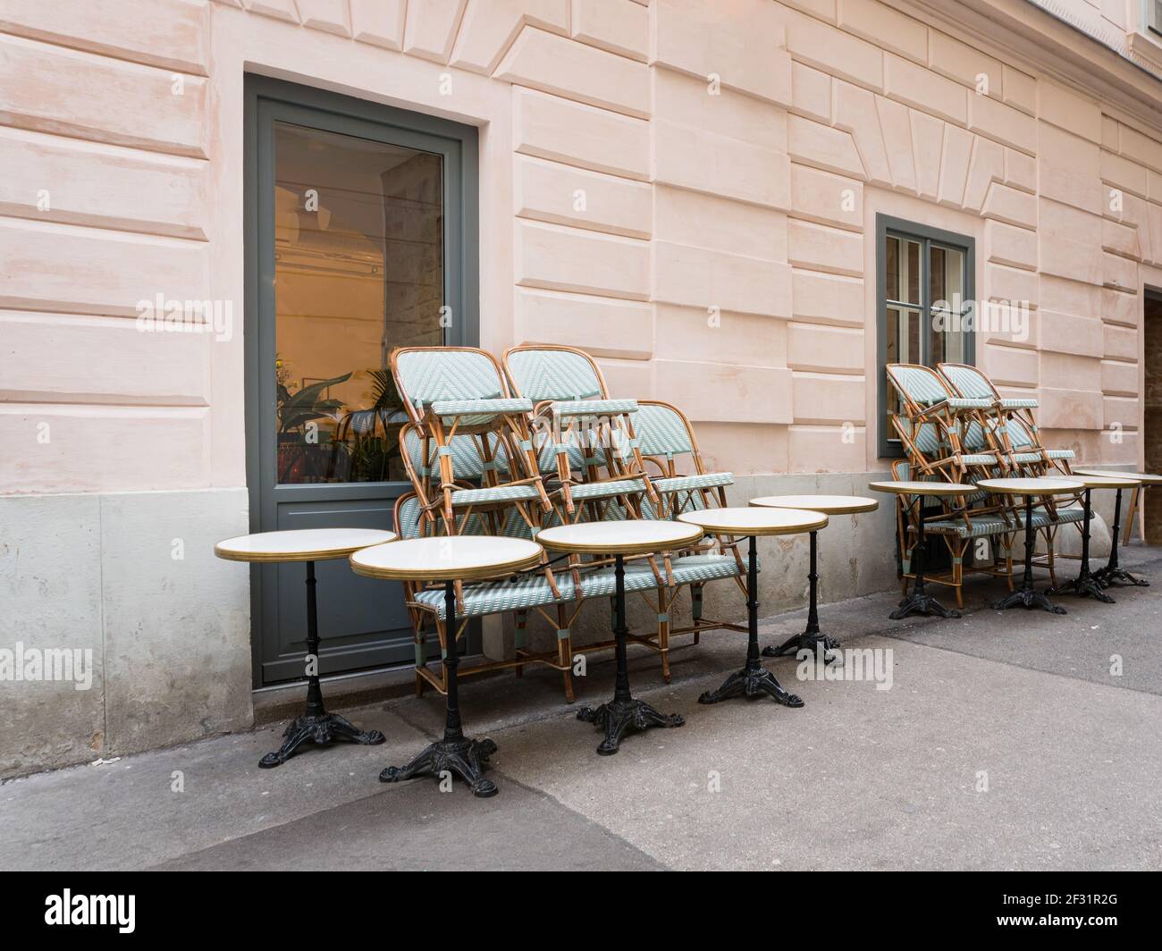 Sedie e sgabelli accatastati sui tavoli di fronte ad un vuoto chiuso ristorante cafè durante Covid-19 Corona pandemic. Foto Stock