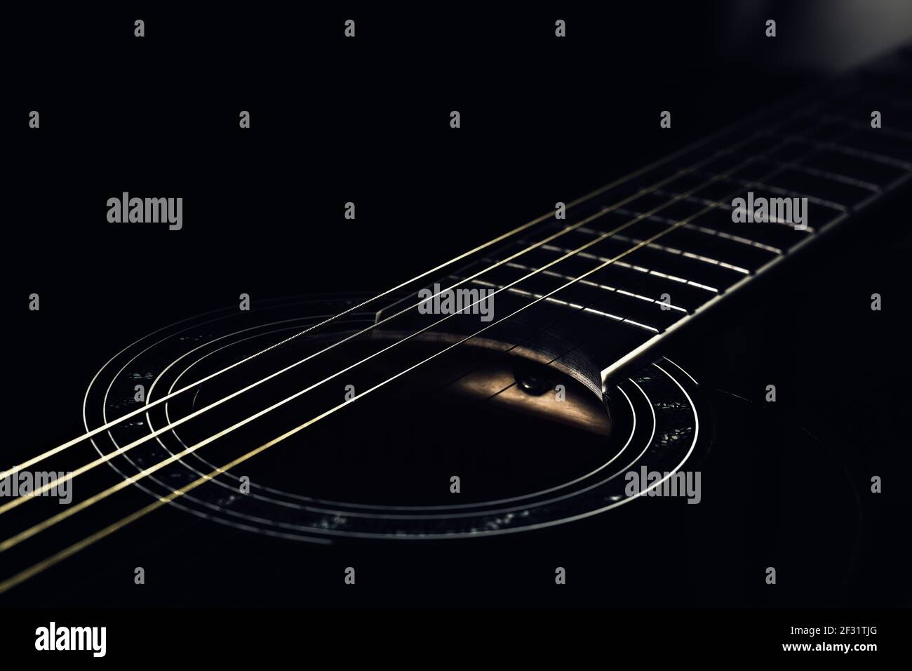 foto di basso-tasto di un frammento di una chitarra nera su uno sfondo scuro. musica chitarra foto estetica Foto Stock
