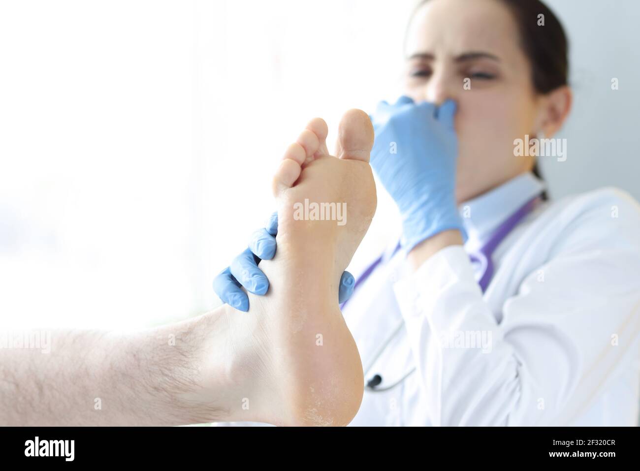 Il medico copre il naso da odore sgradevole dalla gamba maschile Foto Stock