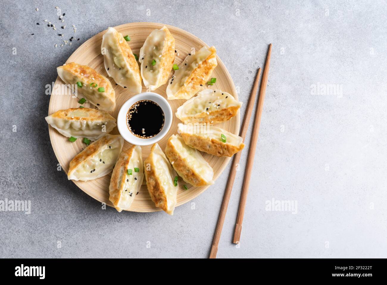 Gnocchi cinesi fritti di Gyoza con carne di pollo serviti con salsa di soia su un piatto di bambù. Vista dall'alto del gyoza del cibo asiatico Foto Stock
