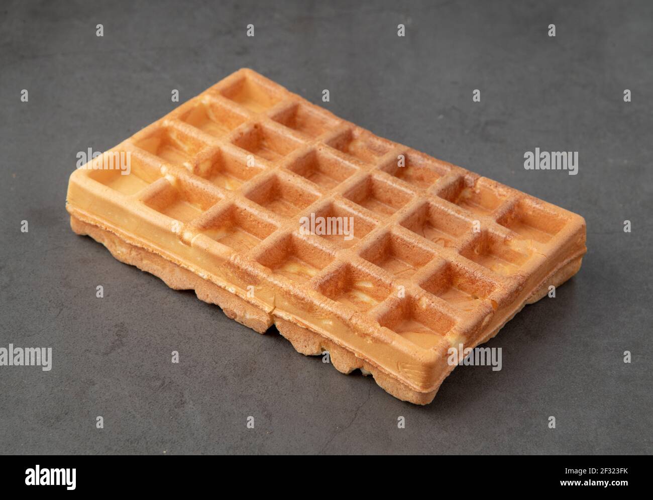 Waffle belgi singoli su sfondo di pietra scuro. Foto Stock