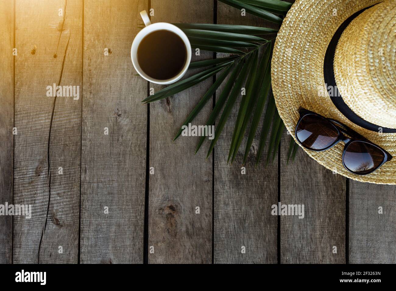 Concetto di viaggio, vacanza. Cappello, foglia di palma, tazza di caffè, occhiali su sfondo di legno. Rilassati. Foto di alta qualità Foto Stock