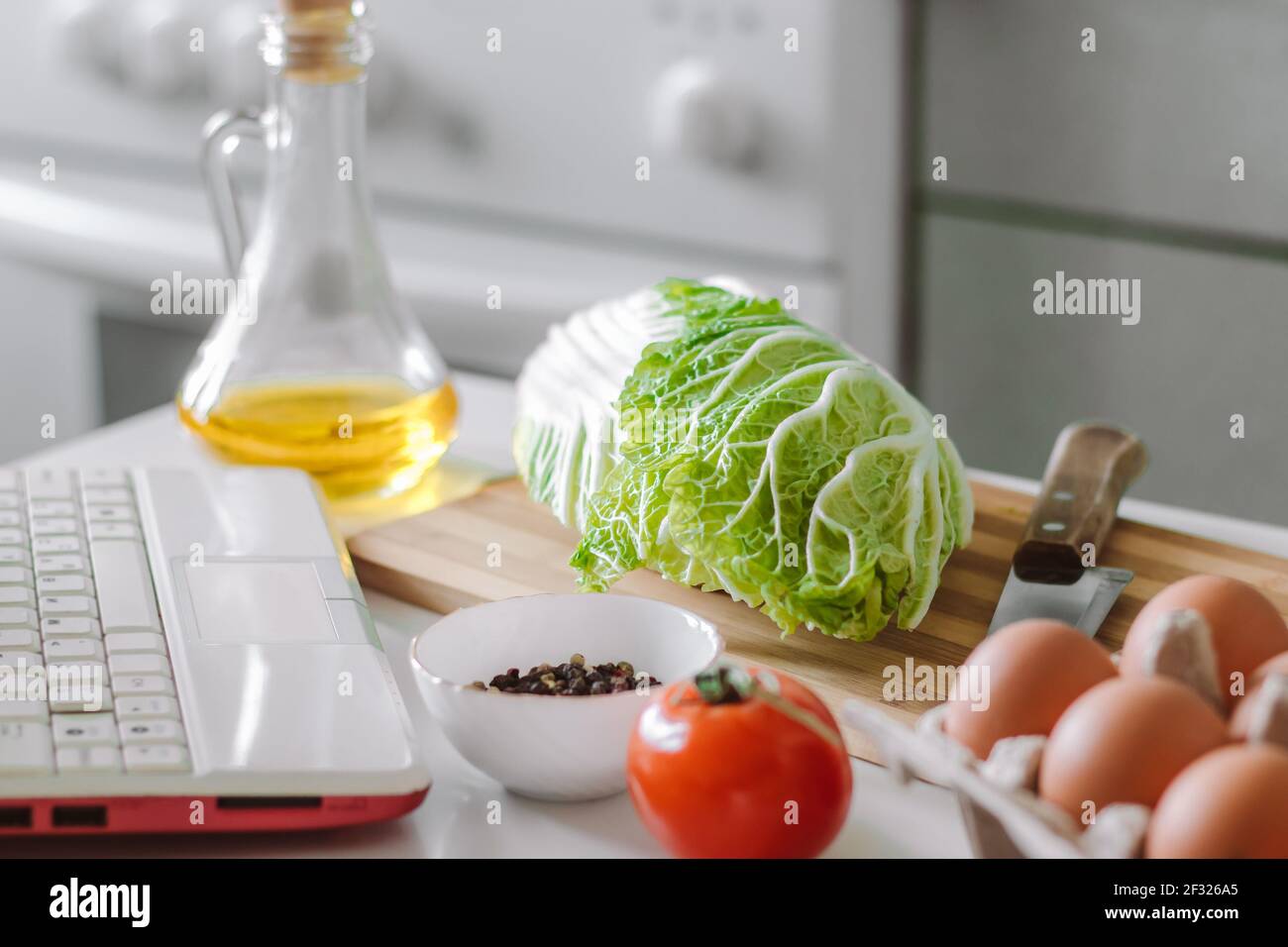 Cucina online. Preparare l'insalata utilizzando il libro di cucina digitale. Verdure fresche e computer portatile in cucina. Foto Stock