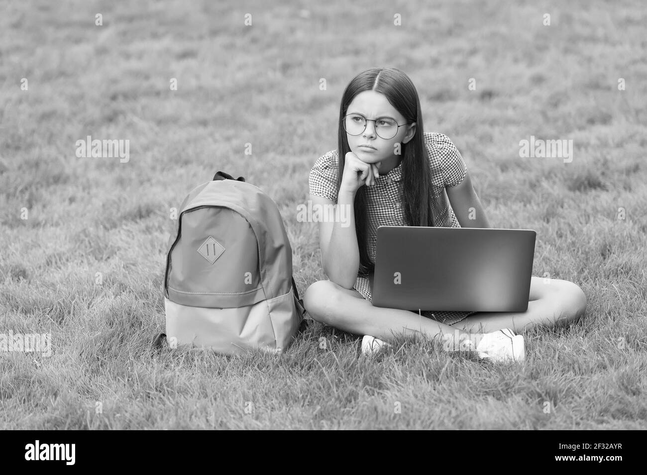 torna a scuola. teen girl usa il computer su erba verde nel parco. bambino con zaino e notebook. nuova tecnologia nella vita moderna. studio. infelice Foto Stock